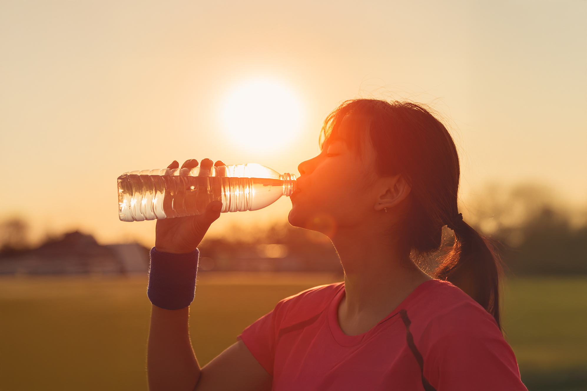 Woman drinking a bottle water on a hot sunny day