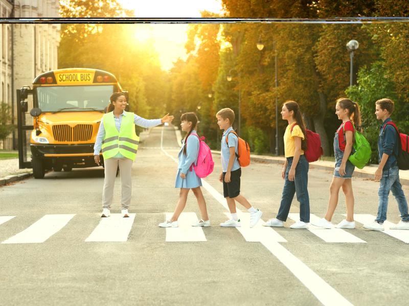 Children walking on a cross walk with a crossing guard